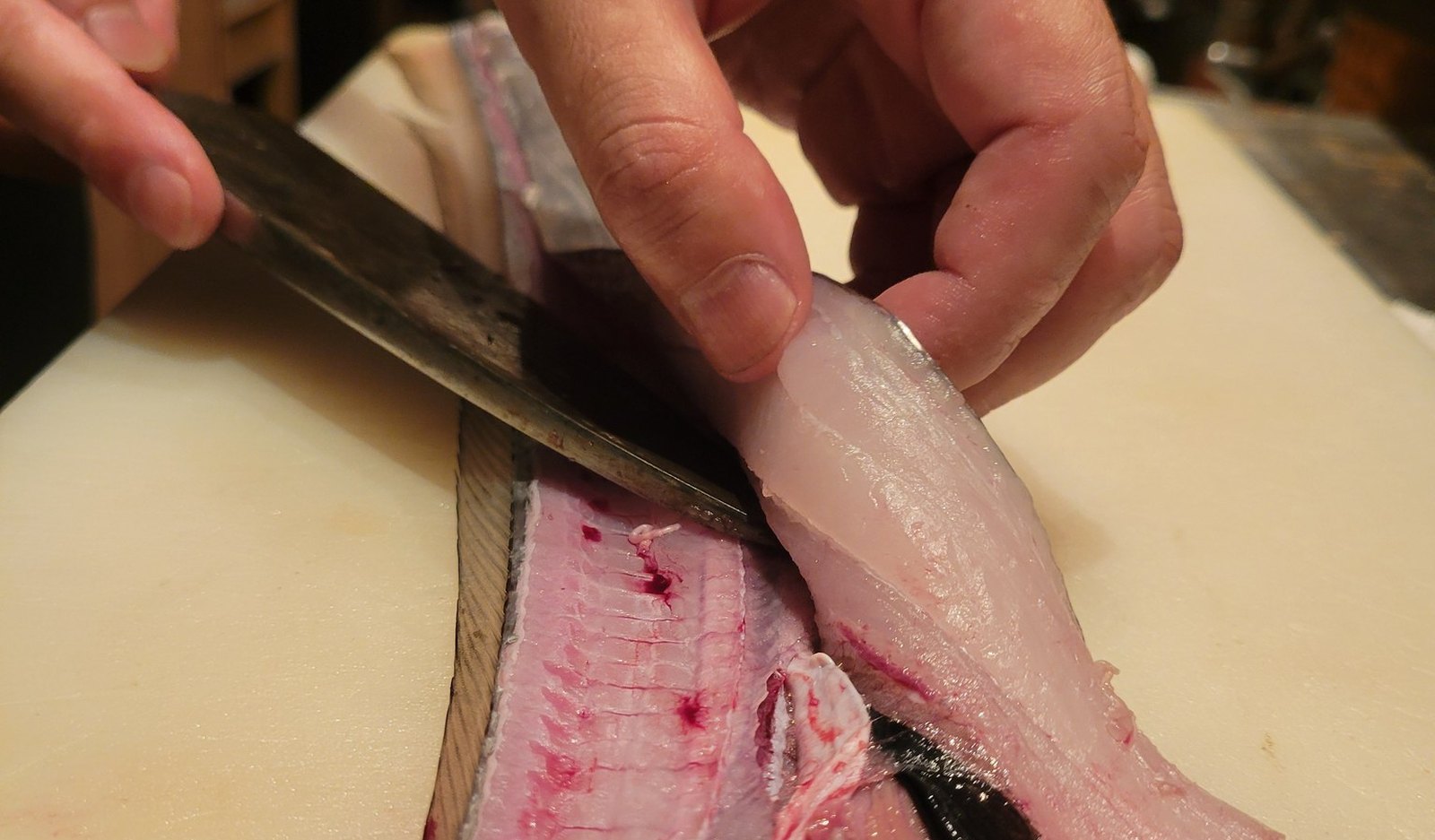 The chef lifting a fillet from a hairtail caught that morning